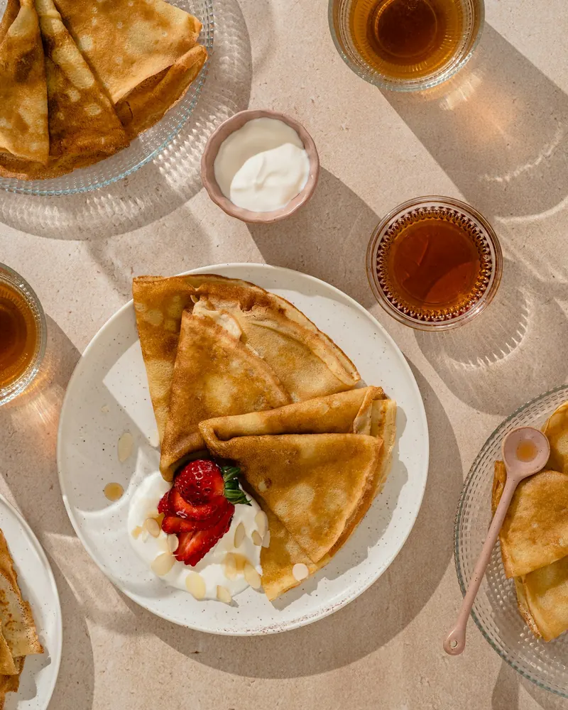 Des crêpes pliées avec des fraises et de la crème