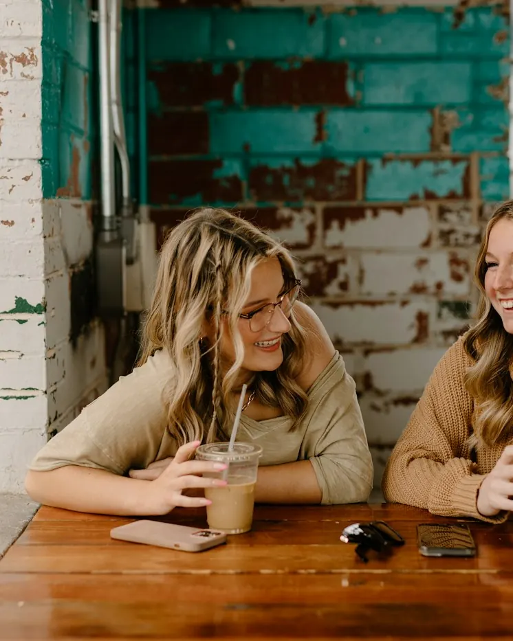 Deux amies rient à une table de café
