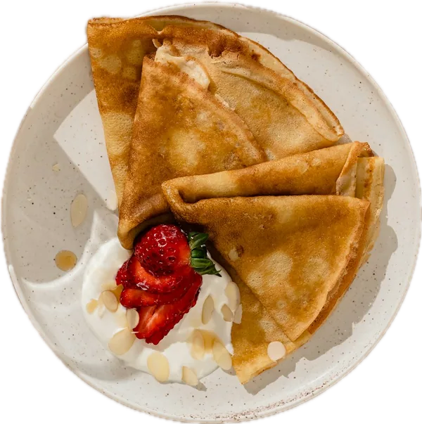 Une assiette de crêpes avec des fraises et de la crème